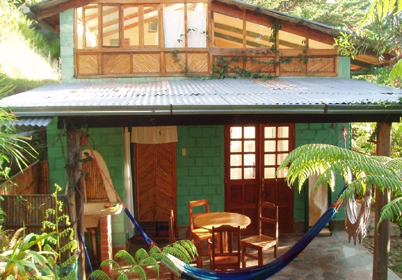 Cabaña con porche, hamacas y mesa exterior rodeada de selva