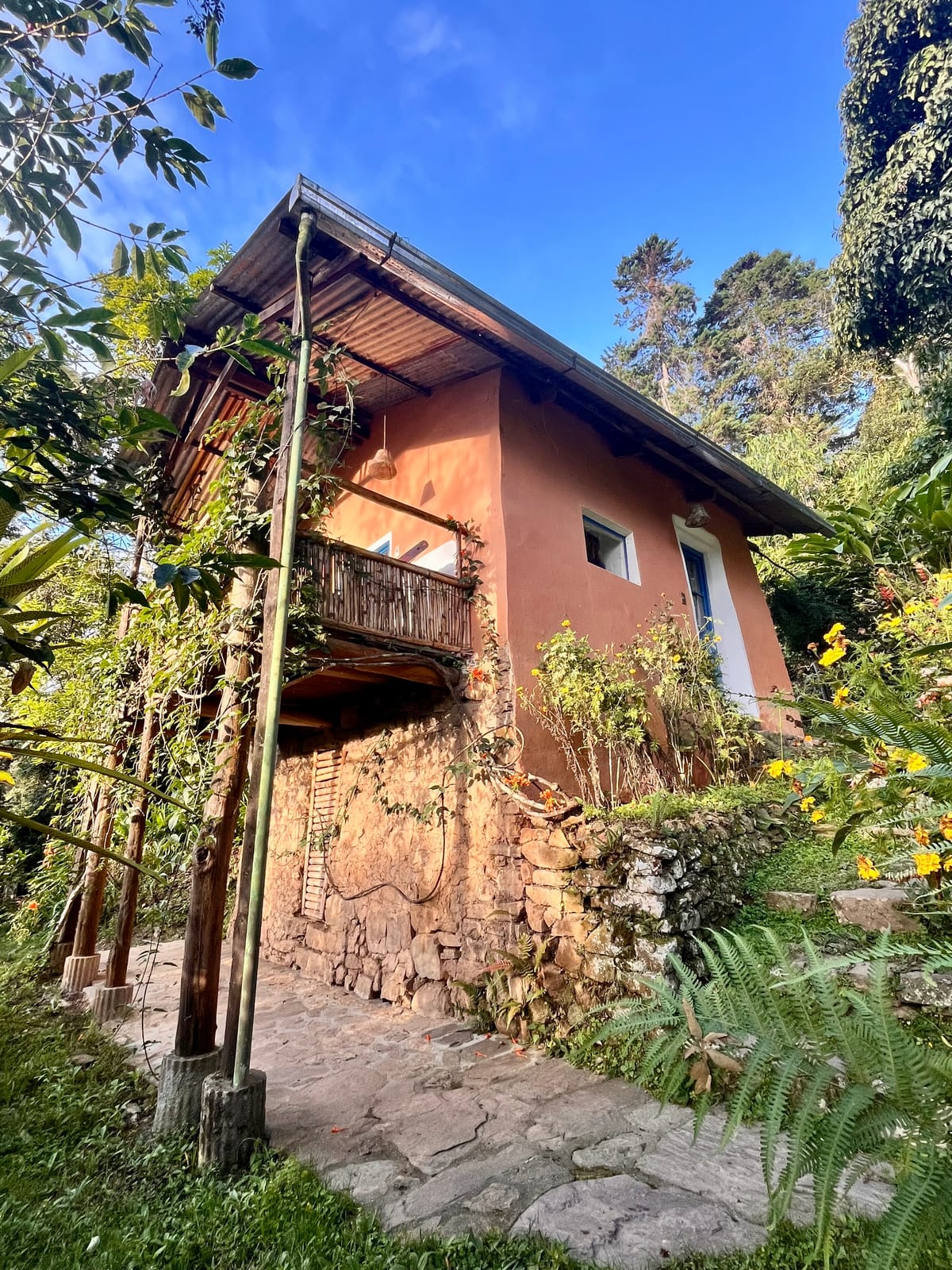 Sendero de piedra junto a una cabaña de adobe, parte de los caminos internos del predio