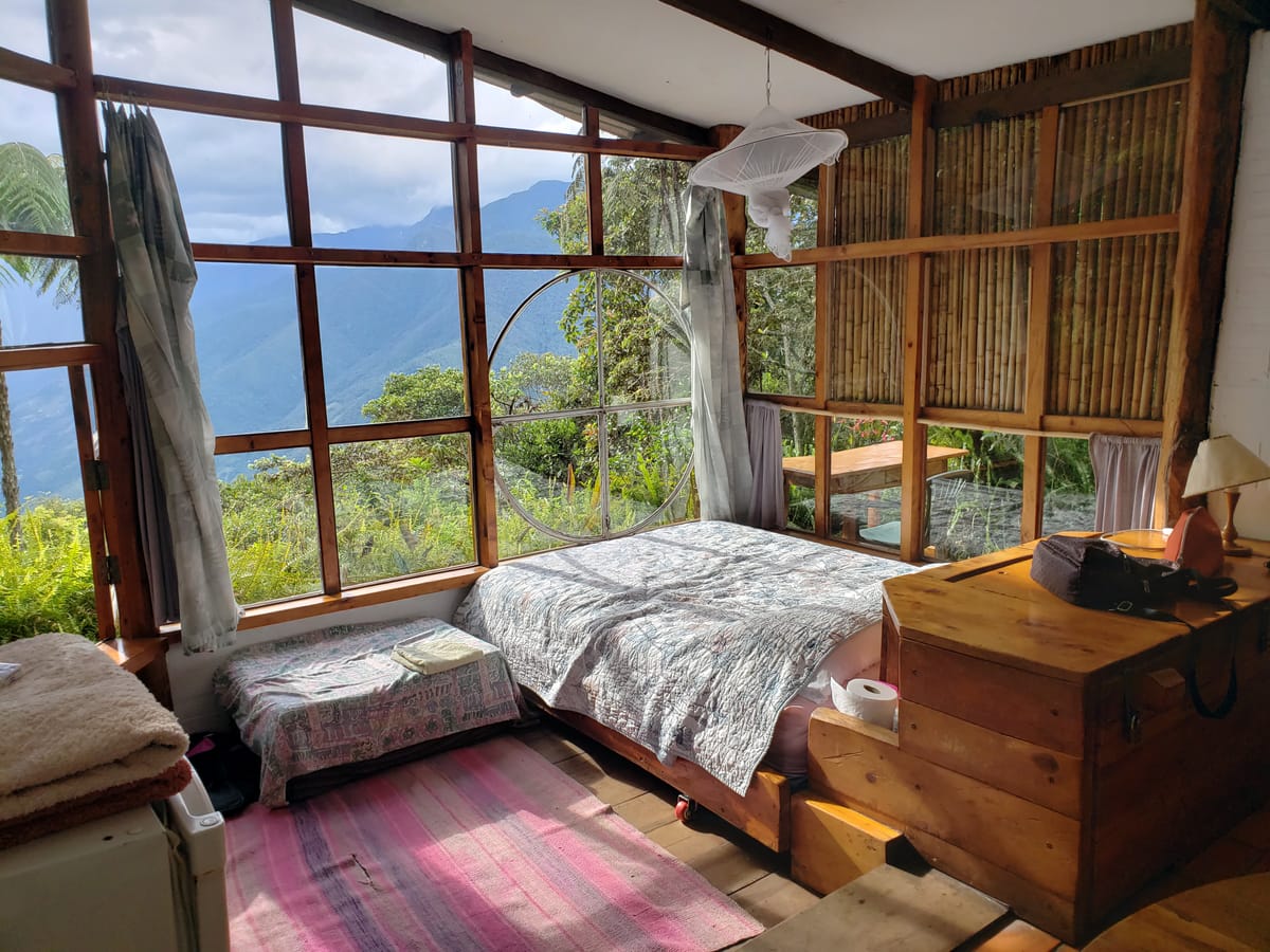 Interior de cabaña de bambú con ventanales y vista a las montañas de Coroico